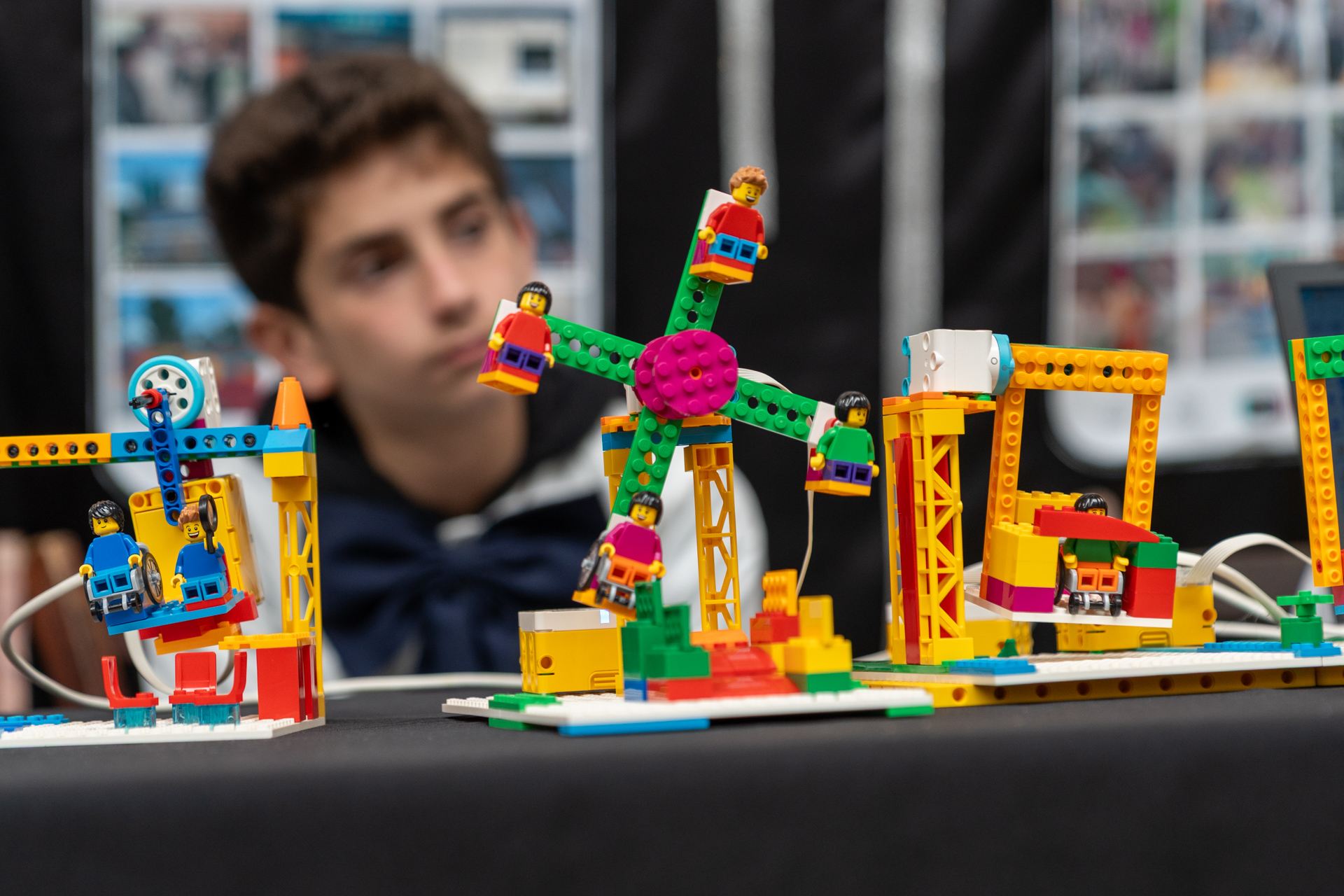 Legos mecanizados sobre una mesa. En segundo plano un niño con moña y túnica blanca encargado de mostrar como funciona este mecanismo. 